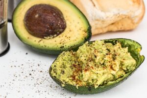 Salsa di avocado fresca in una ciotola con ingredienti naturali sullo sfondo.