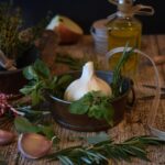 Spicchi d'aglio marinati in un barattolo con erbe aromatiche e olio.