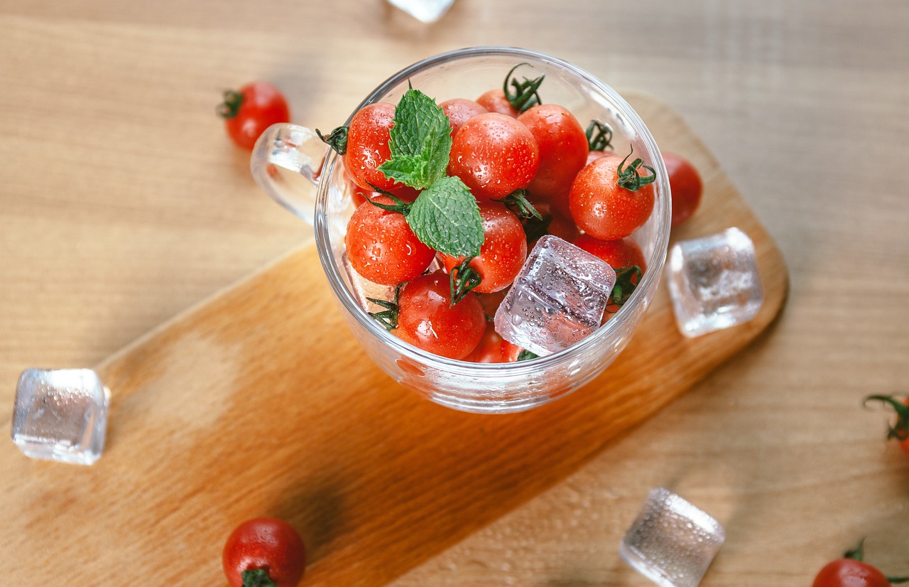 Pomodori freschi su un tagliere, pronti per essere congelati, con utensili da cucina sullo sfondo.